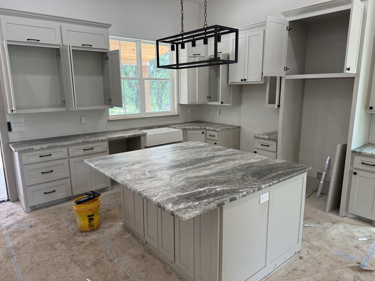 Brown Fantasy marble kitchen island with grey shaker cabinets and farmhouse sink — new construction Central Texas