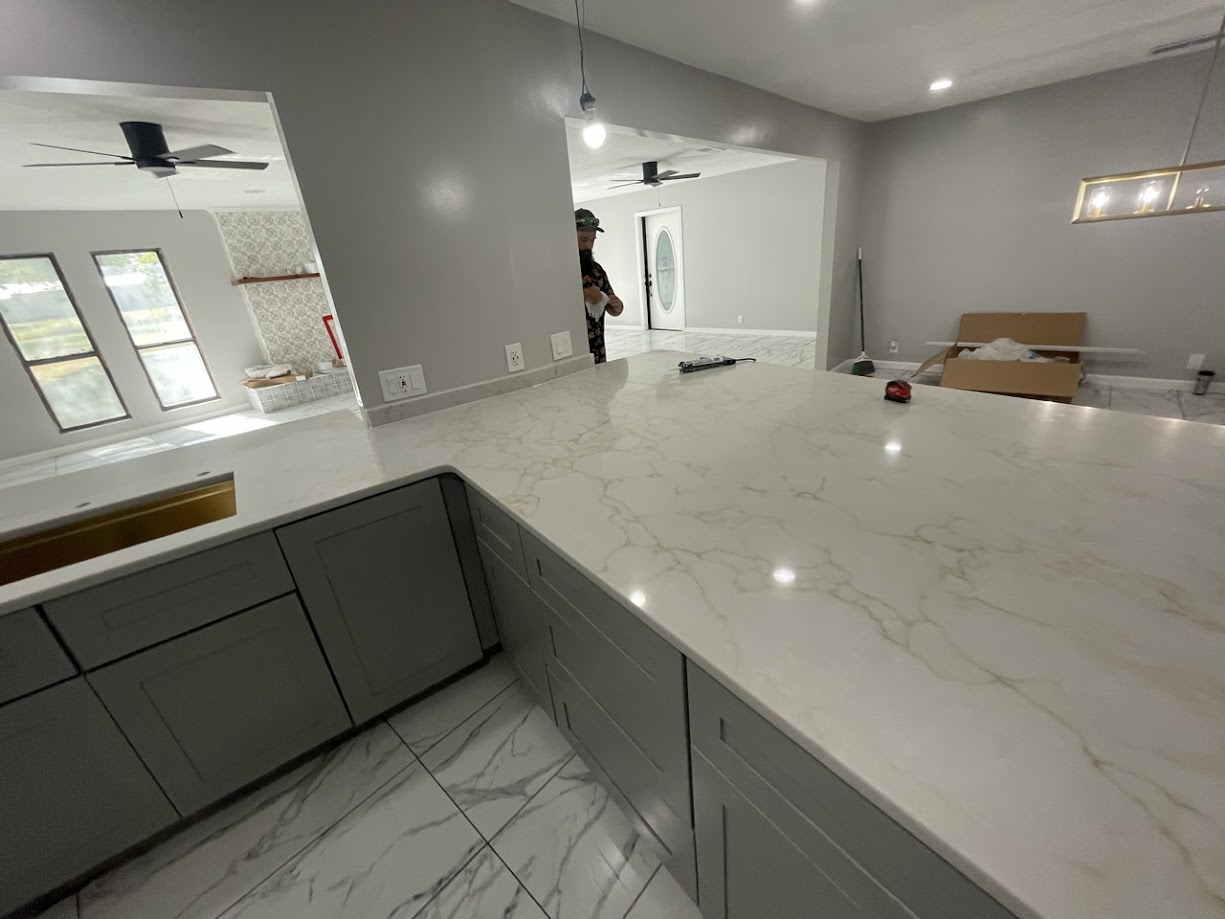 Milan Gold quartz large kitchen peninsula on grey shaker cabinets — new construction Central Texas