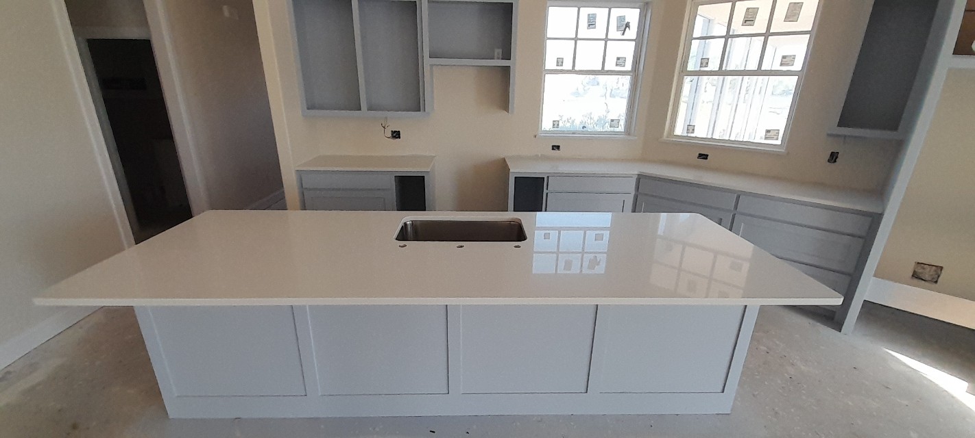 Pure white quartz kitchen island with undermount sink on grey cabinets — new construction Central Texas